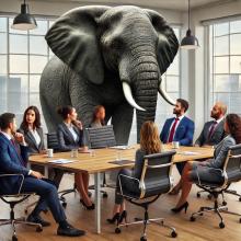 An elephant standing in a room where people are having a business meeting