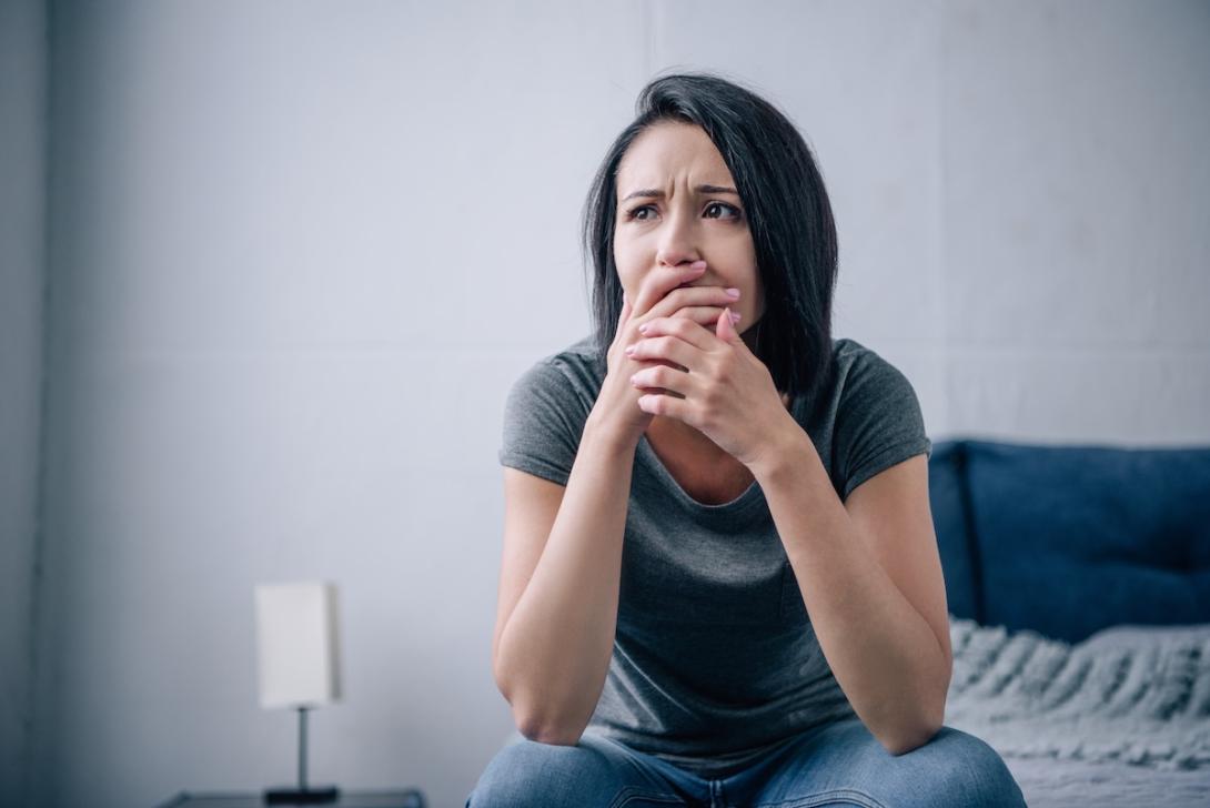 beautiful sad woman covering mouth at home on bed