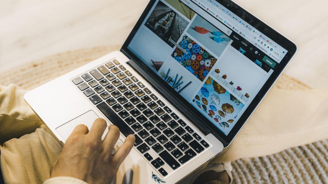 A person using a laptop to browse stock photo websites. Freelancing work in a cozy setting.